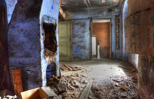 Verfallener Flur mit blauem Kamin und Schutt.